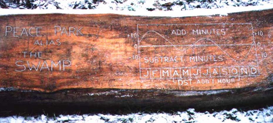 Close-up photo of the adjustment graph carved into the big log behind the sundial
